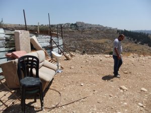 Die wenigen geretteten Habseligkeiten stehen am Wellblechzaun, im Hintergrund eine israelische Siedlung