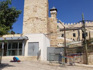 Der Jugendliche betet neben den Checkpoints an der Ibrahimi-Moschee; Foto © EAPPI