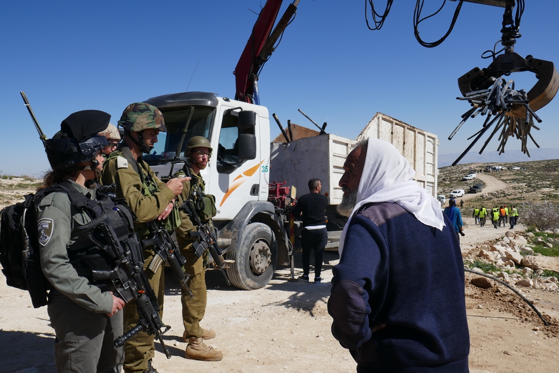 Ein lokaler Schäfer redet mit israelischen Soldaten während der Zerstörung der Wasserleitungen in Massafer Yatta; Foto © EAPPI 