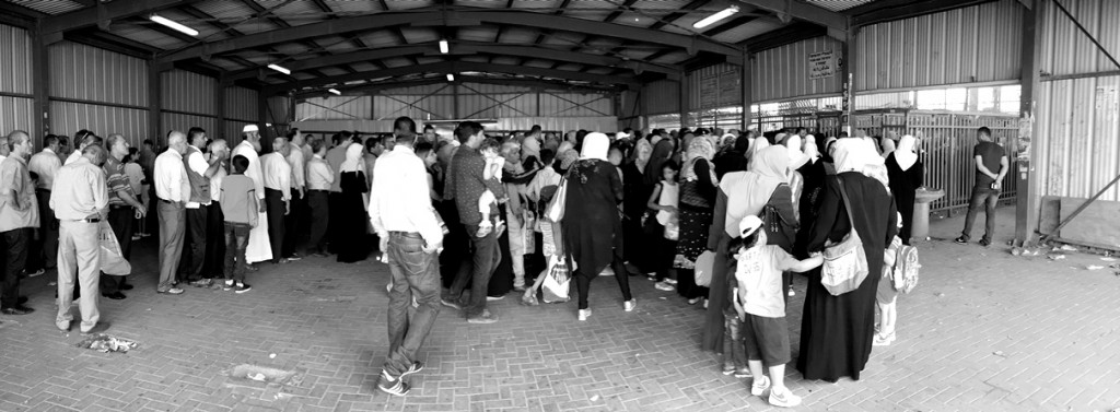 In einer großen Wartehalle stehen die Menschen an, um sich dann in einen der drei extrem schmalen Gittergänge zu begeben, an dessen Ende ein Drehkreuz den Zugang zum Innenbereich des Checkpoints steuert. Hinter dem Drehkreuz sortieren sich die Menschen in mehrere Durchgänge ein, an denen sie Jacken und Taschen durch einen Metalldetektor laufen lassen und ihre unterschiedlichen Dokumente zur Identifikation an ein kugelsicheres Fenster halten sowie ihre Finger auf die Maschine zum Lesen der Abdrücke legen.