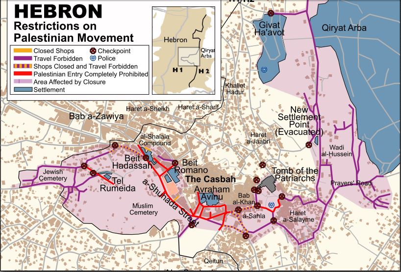 Karte ©B’Tselem: Die Karte zeigt den israelisch kontrollierten Teil von Hebron (H2). Hellblau sind die vier israelischen Siedlungen dargestellt. Die Straßen, die diese vier Siedlungen verbinden, dürfen von Palästinensern zum größten Teil nicht betreten werden (rot unterlegte Straßen). Etwas außerhalb der Innenstadt liegen die zwei große Siedlungen Qiryat Arba und Givat Ha’avot. Auf den Straßen entlang dieser Siedlungen dürfen Palästinenser nur zu Fuß gehen (lila unterlegte Straßen). Die dunkelroten, durchkreuzten Kreise zeigen die 16 Checkpoints der Stadt. An den meisten steht rund um die Uhr mindestens ein*e Soldat*in, der*die die Ausweise der Passanten kontrolliert. Einige Checkpoints sind weniger als 50 Meter voneinander entfernt.