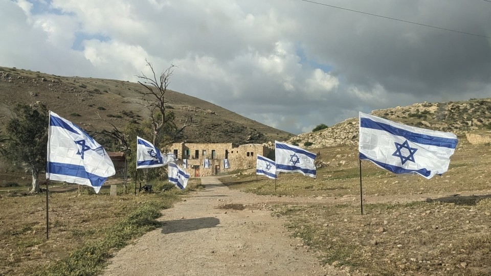 Die Zufahrtsstraße zur Gemeinde, im April 2026 gesäumt von israelischen Flaggen; Foto: lokaler Kontakt, im Rahmen der laufenden Begleitung durch das WCC-EAPPI zur Verfügung gestellt