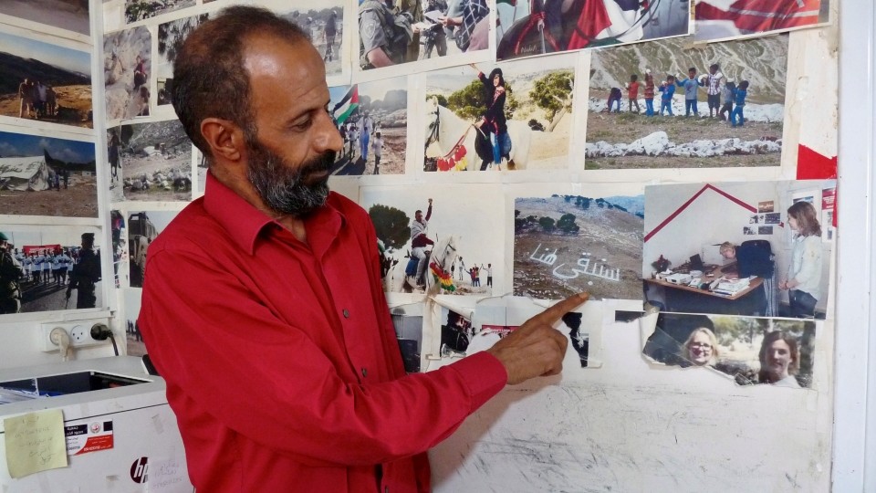 Attalah zeigt uns das Foto mit den aus Steinen gelegten arabischen Worten „Wir bleiben“; Foto WCC-EAPPI/Monique