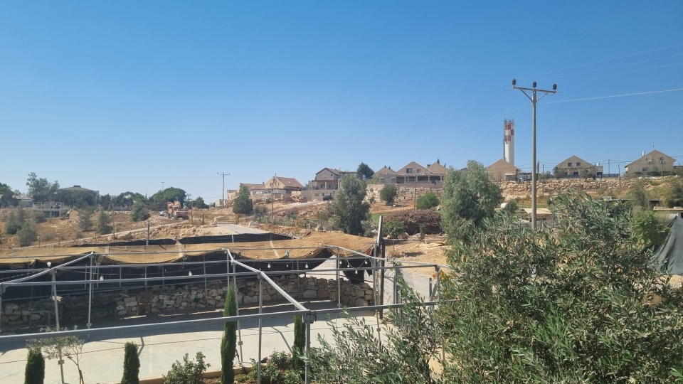 Basketballplatz des Gemeindezentrums von Umm al Kheir, dahinter die völkerrechtswidrige Siedlung Karmel. Unten links ist der Steinkreis zu erkennen, der den Todesort von Awdah Hatheleen kennzeichnet; © WCC-EAPPI/Marvin