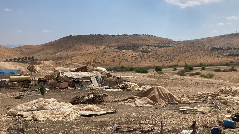Wie hier in Farisiya leben die Hirt:innen und Beduinen im Jordantal zumeist in einfachsten Umständen, da ihnen das Errichten von dauerhaften Strukturen wie etwa festen Häusern auf ihrem Land von den israelischen Behörden untersagt wird. Im Hintergrund liegt auf dem Hügel die völkerrechtswidrige israelische Siedlung Rotem Foto © WCC-EAPPI/Maria